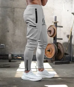 Detail of grey slim-fit cargo joggers with black zipper pockets in gym setting