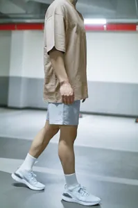 Vue de côté d'un homme portant un t-shirt en coton oversize kaki et un short de sport