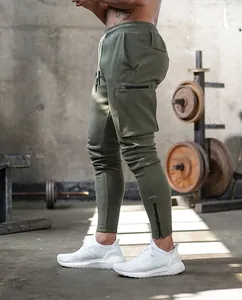 Side view of olive green cargo joggers with ankle zippers in a professional gym setting.
