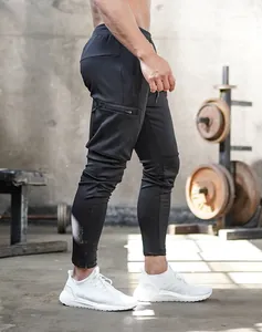 Side detail of black slim-fit men's fitness joggers with zipper pocket in a gym setting