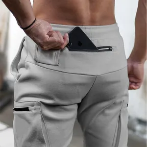 Detail of men's grey athletic joggers showing a functional zippered back pocket for phone storage.