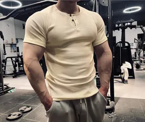 Close-up of men's slim fit ribbed muscle t-shirt with Henley neck in a gym setting.
