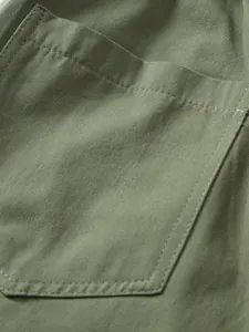 Close-up detail of the woven fabric and pocket stitching on men's olive green shorts.