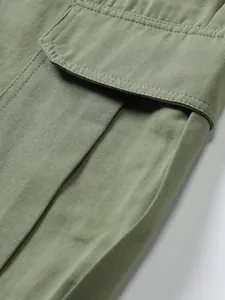 Close-up view of olive green woven fabric texture and pocket detail on men's cargo shorts