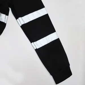 Gros plan d'une manche de sweat à capuche noir avec des bandes réfléchissantes.