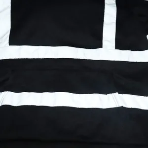 Détail rapproché des bandes réfléchissantes de sécurité blanches sur un sweat à capuche noir