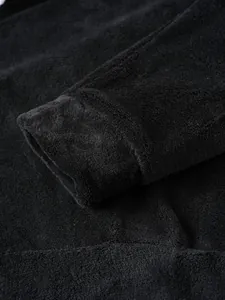 Detailansicht des weichen Korallenvlies-Ärmelbündchens an einem schwarzen Herrenpulli