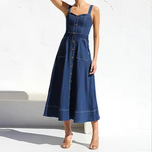 Vista dettagliata di un abito midi in denim blu scuro con bottoni e cuciture a contrasto e tasche.