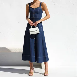 Vista dettagliata di un abito midi in denim blu scuro con bottoni e borsetta bianca.