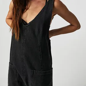 Detail shot of the V-neck design and front pockets on black denim overalls jumpsuit.