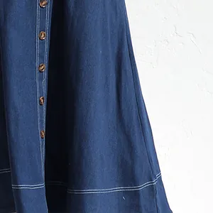Dettaglio di un abito in denim blu con bottoni marroni retrò e cuciture bianche