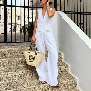 Dettaglio di un set in lino bianco con gilet senza maniche e pantaloni larghi su modella