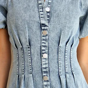Close-up detail of a vintage washed denim dress featuring metal buttons and waist pleats.