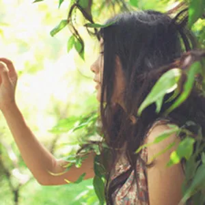 Close-up of a woman wearing a slim-fit U-neck t-shirt in a lush green garden setting