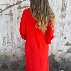 Back view of a red loose-fit dress with lantern sleeves and textured fabric detail