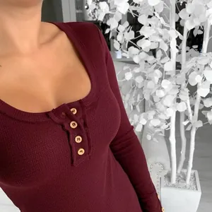 Close-up of burgundy waffle knit U-neck top with wooden buttons and slim fit texture