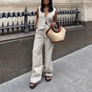 Foto lifestyle di una donna con un set di gilet in lino e pantaloni larghi color beige