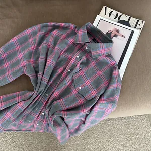 Dettaglio di una camicia a maniche lunghe a quadri grigi e rosa con tasche e colletto
