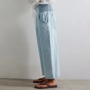 Side view of women's light blue washed denim harem pants with a comfortable elastic waist