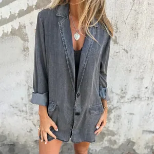 View of women's oversized washed grey denim blazer worn by model against a textured wall