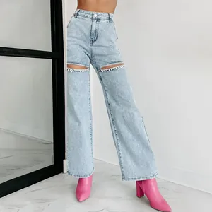 Detail view of high-waisted straight jeans with rhinestone-trimmed knee cutouts