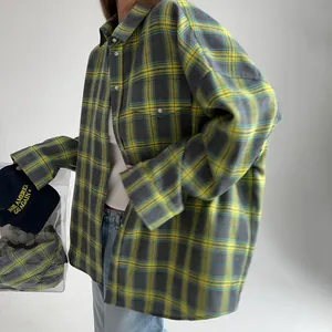 Dettaglio della camicia a quadri gialla e grigia oversize con taschino e colletto.