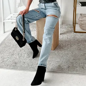 Detailed view of silver rhinestone-trimmed cutouts on light blue distressed jeans for women