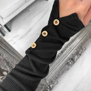 Detail of black ribbed knit sleeve featuring wooden buttons and thumbhole design