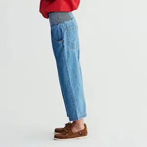 Side view of women's blue washed harem jeans with a comfortable elastic waistband.