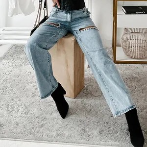 Detailed shot of studded rhinestone cut-outs on light blue straight-leg jeans