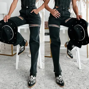 Detail view of black distressed jeans with rhinestone studs and knee cut-outs