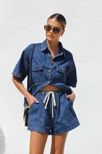 Stylish women's summer denim set featuring a short-sleeve shirt and drawstring shorts.