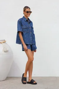 Side view of woman in casual loose blue denim short sleeve shirt and shorts set