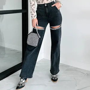 Detailed view of women's straight-leg denim jeans with rhinestone knee cutouts