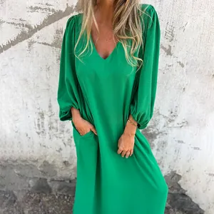 Close-up of loose green V-neck dress with lantern sleeves and pockets on model