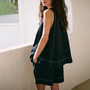 Side view of women's sleeveless black denim two-piece set with white contrast stitching.