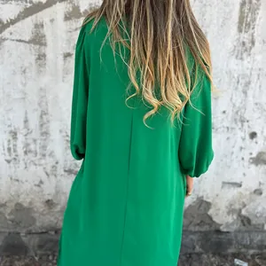 Detail view of a loose green lantern sleeve dress showing back design and fabric texture