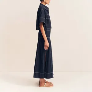Side view of navy denim two-piece set with white contrast stitching and side split.