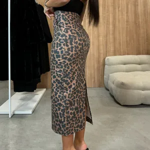 Side view detail showing the slim fit of a high-waisted leopard print midi skirt with back slit