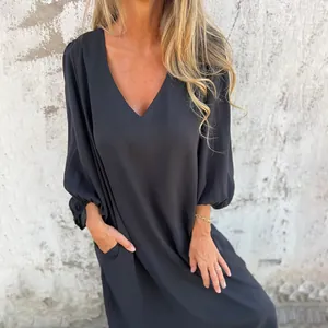 Detail of loose black V-neck dress with lantern sleeves and functional side pockets