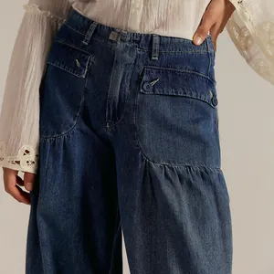 Close-up of loose mid-waist denim jeans with unique ruffled pocket design and buttons.