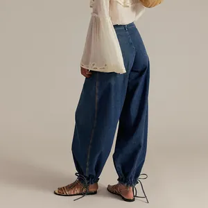 Detail view of women's loose washed denim pants featuring unique drawstring cuffs and hem.