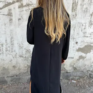 Back view of a long-sleeved black casual dress with a side slit and loose fit silhouette