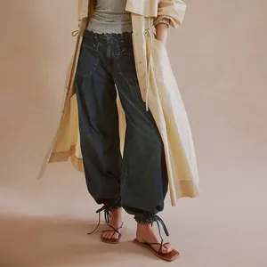 Detail view of women's loose washed denim jeans featuring stylish adjustable ankle ties
