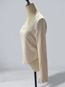 Side view of off-white ribbed long sleeve top with curved hem on mannequin in warehouse.