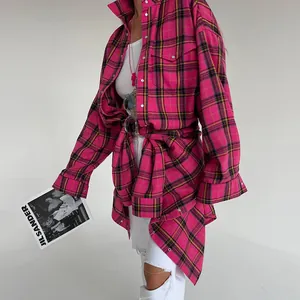 Vista dettagliata della camicia scozzese rosa vintage a maniche lunghe da donna con jeans bianchi.