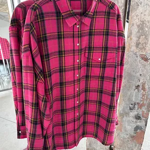 Dettaglio di una camicia di flanella a quadri rosa oversize stile vintage.