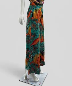 Detailed side view of teal and orange tropical print wide-leg pants on a white mannequin
