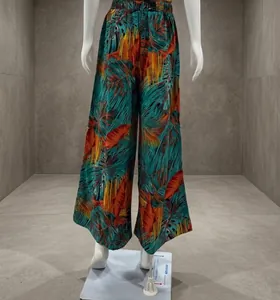 Detailed view of vibrant tropical palm leaf print wide-leg trousers on a display mannequin