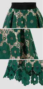 Détail du tissu en dentelle florale vert foncé avec motif ajouré sur une jupe midi vintage.